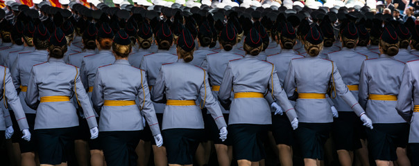 Military women in colorful uniform gracefully marching during victory day parade, back view, panoramic crop.