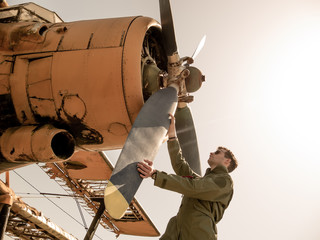 A handsome young pilot standing next to the propeller