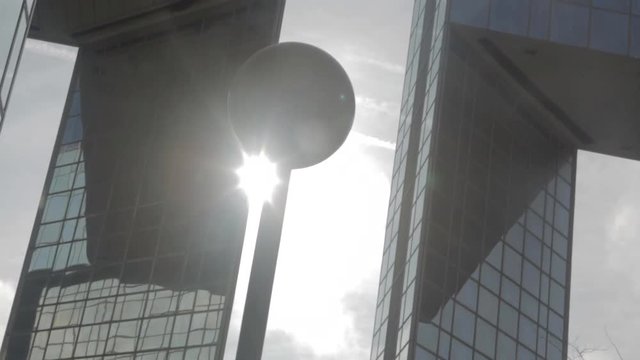 Street Lamp with Spider web and light flares with building reflected on glass skyscraper in Paris with low camera movement, grey skyscraper, cloudy blue sky and reflections. Big sun.