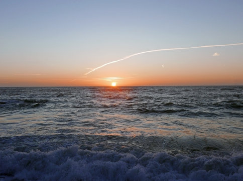 il sole arancione che si tuffa nel mare scuro