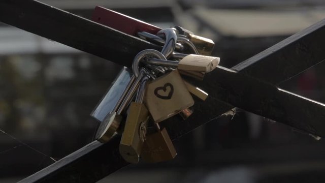 Love locks padlocks on the love bridge, Pont des Arts, in Paris on a sunny summer afternoon with the river in the background and a tourist boat passing by. Padlock on bridge with blurred water.