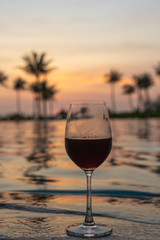 Glass of red wine with swimming pool background