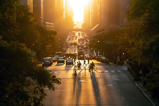 Sunset over 42nd Street casts long shadows from the people and cars in Midtown Manhattan, New York City