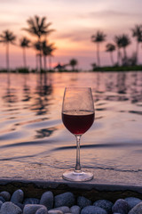 Vertical photo of glass of wine on swimming pool resort background
