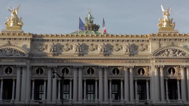 Parisian monument background at Opera place. Gold statue historical sculptures with french flag and european UE flag fluttering in the wind with beautiful blue sky during summer afternoon in Paris.