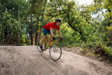 A cyclist rides on a road bicycle, coming down hill.