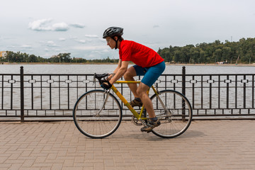 A cyclist rides on a road bicycle along lake.