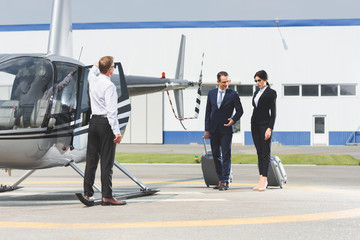 business partners in formal wear with suitcases near pilot and helicopter © LIGHTFIELD STUDIOS