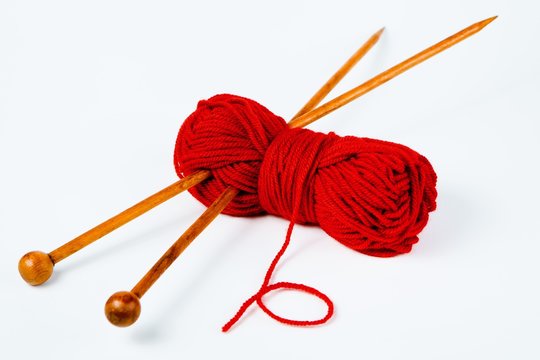 Pair of wooden knitting needles and red wool - white background