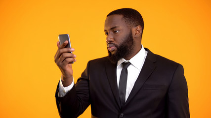 African-american businessman holding smartphone, mobile financial tool, app