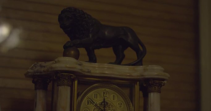 Close up of an old marble clock with a black lion sculpture in a creepy haunted house on a winter night. Tilt up. Halloween scary ambiance. Ghost, Demon or Spirit. Shot on RED SCARLET 6K.