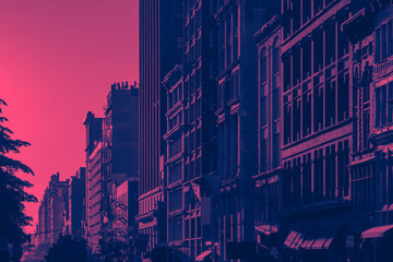Sunlight shines on New York City buildings with pink and blue color cast