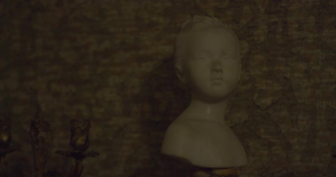 Sculpture of child's head moving alone and turning his head in a creepy haunted house on a winter night. Halloween scary ambiance. Ghost, Demon or Spirit. Shot on RED SCARLET 6K.
