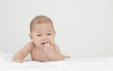 portrait of little small asian baby infant relaxing after bath looking to the right side with his finger in mouth