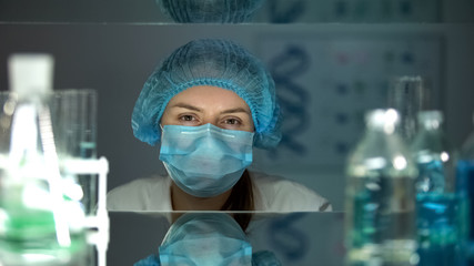 Female chemical in protective uniform looking at camera, working in laboratory