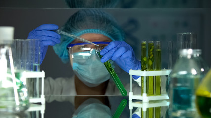 Biologist adding liquid in tube with green plant preparing extraction medication