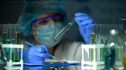 Researcher analyzing transparent blue liquid, water contamination prevention