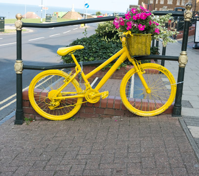 Yellow painted old fashioned bicycle on display