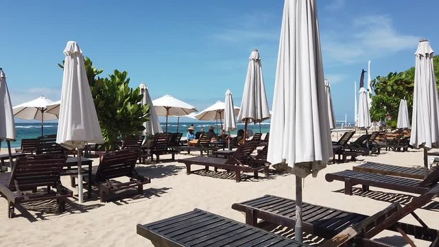on the beach there are unfilled sunbeds and umbrellas from the sun. the video shows how the wind shakes umbrellas. Indonesia, Bali, Nusa Dua.