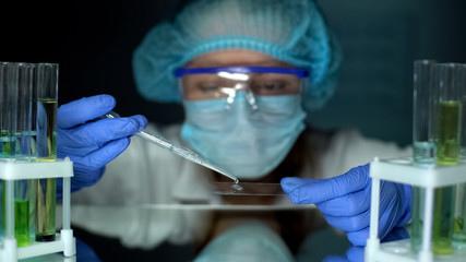 Scientist dripping water sample on test glass, heavy metals analysis, laboratory