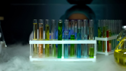Biologist looking at test tubes with samples in refrigerator, laboratory work