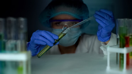 Researcher opening refrigerator and dripping oily substance in yellow liquid