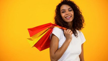 Smiling Afro-American woman holding shopping bags, Black Friday discount