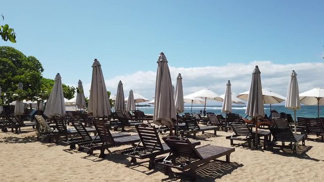 on the beach there are unfilled sunbeds and umbrellas from the sun. the video shows how the wind shakes umbrellas. Indonesia, Bali, Nusa Dua.