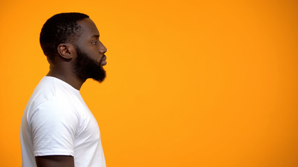 Side view of young Afro-American male against yellow background, advertisement