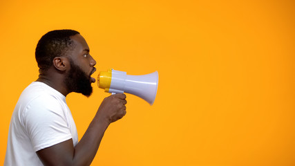 African-American man using megaphone for protest, calling to action, side view