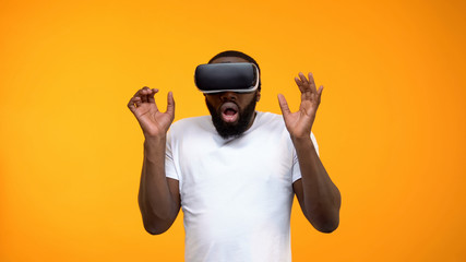 Scared African-American man using virtual reality headset, simulation, close-up