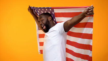 African-American man holding USA flag, supporting national sports team, fan