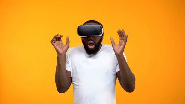 Scared African-American man using virtual reality headset, simulation, close-up