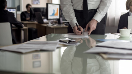 Male CEO signing contract, employees working on background, paperwork in office