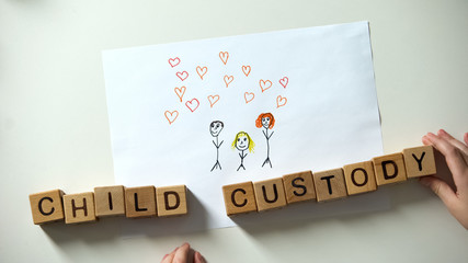 Kids hand putting child custody phrase made of cubes on family picture, orphan