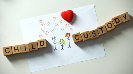 Child custody phrase made of cubes lying on family painting sides, orphan dream