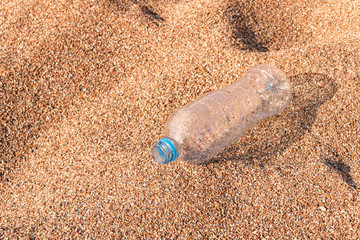 water flows out of a plastic bottle on the sea sand. water saving. last water drop