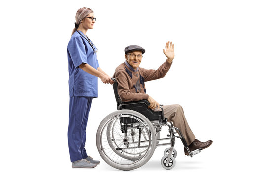 Female Nurse Pushing A Senior Patient Sitting In A Wheelchair And Greeting With Hand