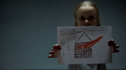 Girl showing house on fire picture into camera, assault and violence in family
