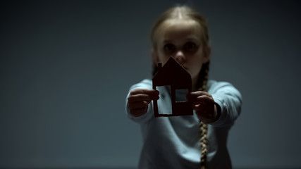 Child showing paper house into camera, refugee looking for shelter, orphan
