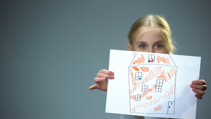 Kid showing house picture into camera, poor family needing home, social support