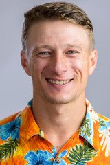 Portrait shot of young happy Caucasian man in Hawaiian shirt iso