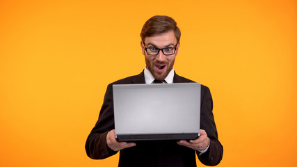 Surprised man reading good news on laptop, online shopping, internet store sale