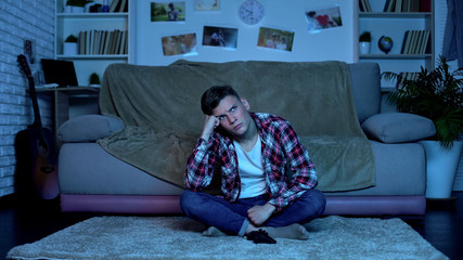 Obraz premium Alone boy sitting on floor of room watching tv, lack of friends, boredom