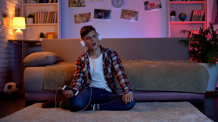 Obraz premium Young man listening to music from smartphone in headset in his room, hobby