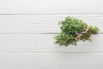 top view of fresh green thyme on white wooden table