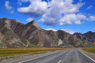 Naklejka premium Empty road to the mountains on a sunny day.