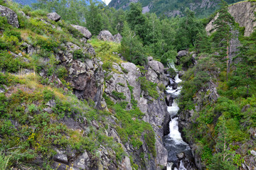 Top view on the waterfall among trees and rocks.