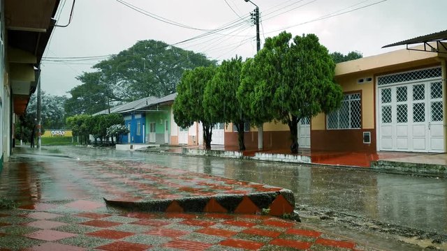 Lluvia fuerte en calle de poblado, aguacero, invierno, calle mojada, diluvio, arboles casas paisaje antural