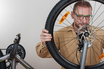 Bearded man puts the front wheel on the bicycle.